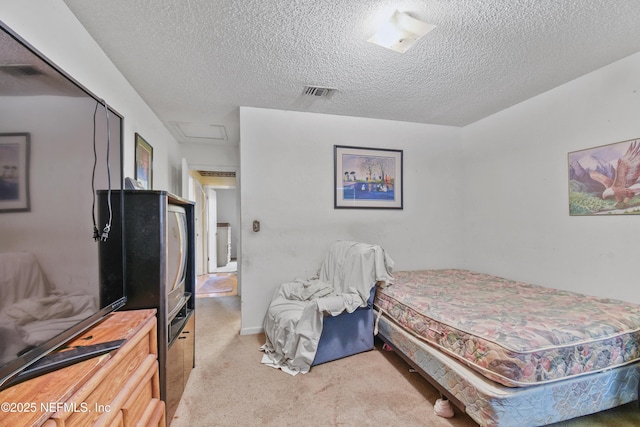 carpeted bedroom featuring attic access, visible vents, and a textured ceiling