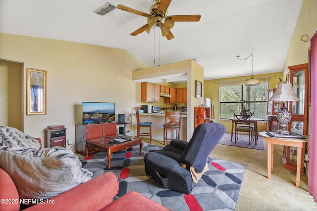 living area with light carpet, vaulted ceiling, a textured ceiling, and visible vents