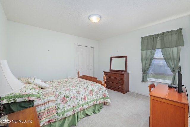 bedroom featuring light carpet, a closet, a textured ceiling, and baseboards