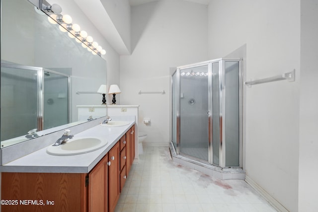 bathroom with toilet, a shower stall, double vanity, and a sink