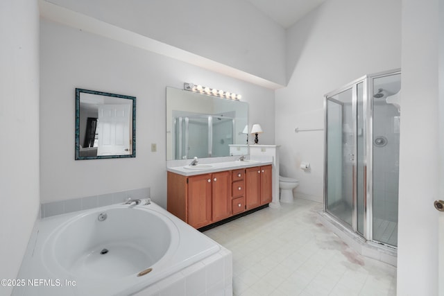 bathroom featuring a garden tub, double vanity, toilet, a sink, and a shower stall