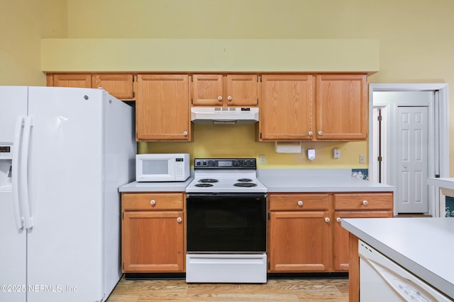 kitchen featuring white appliances, under cabinet range hood, light countertops, and light wood-style floors