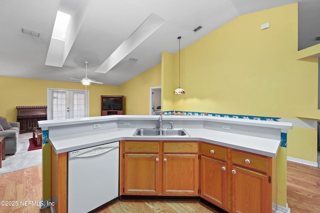 kitchen with open floor plan, hanging light fixtures, white dishwasher, light countertops, and a sink