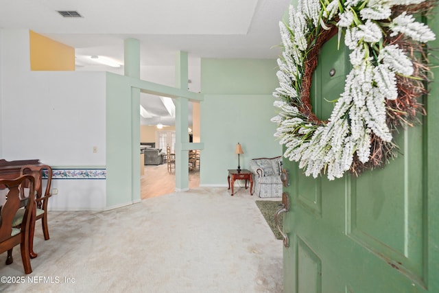 foyer entrance featuring visible vents and light colored carpet