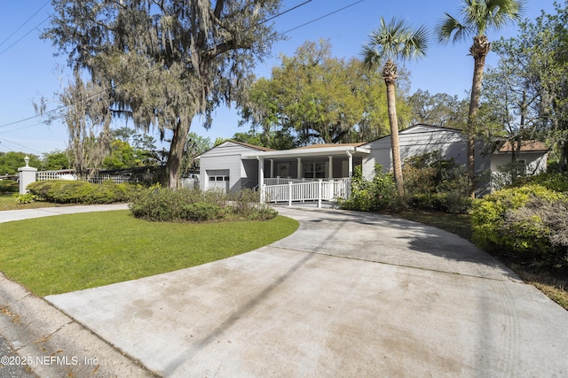 view of front of property with a garage, concrete driveway, covered porch, fence, and a front yard