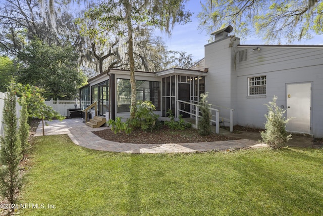 rear view of property with a sunroom, a chimney, fence, and a yard