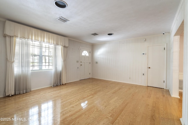 foyer with light wood-type flooring, visible vents, crown molding, and baseboards