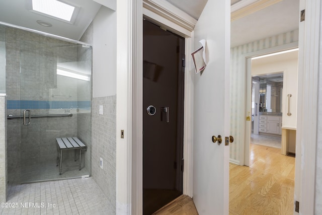 bathroom with a stall shower, vanity, tile walls, and wood finished floors