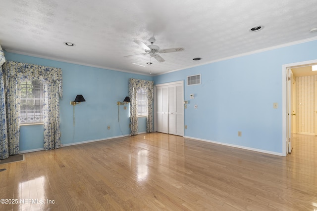 unfurnished room featuring baseboards, wood finished floors, visible vents, and crown molding