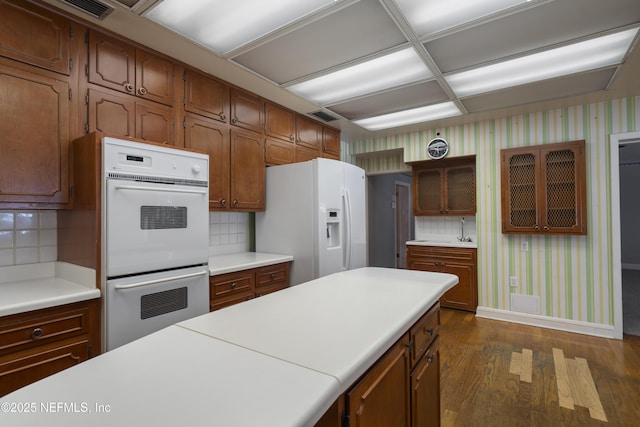 kitchen featuring light countertops, white appliances, dark wood finished floors, and wallpapered walls