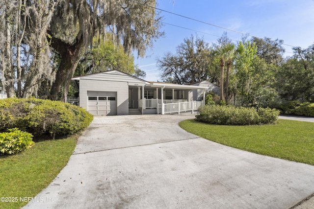 ranch-style home with concrete driveway, a porch, a front lawn, and an attached garage