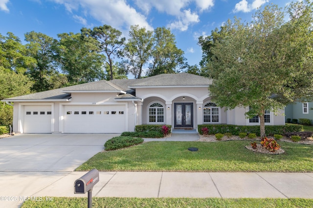 single story home with french doors, stucco siding, an attached garage, driveway, and a front lawn