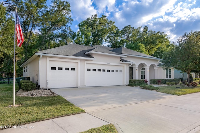 view of front of house with a garage, a front lawn, concrete driveway, and stucco siding