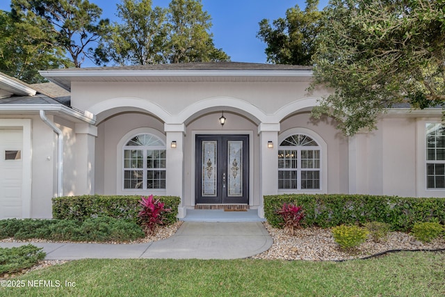 view of exterior entry featuring a garage and stucco siding