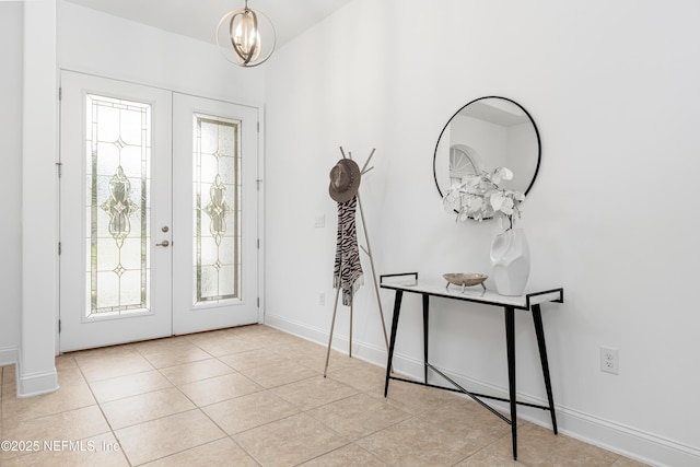 foyer featuring a chandelier, french doors, light tile patterned flooring, and baseboards