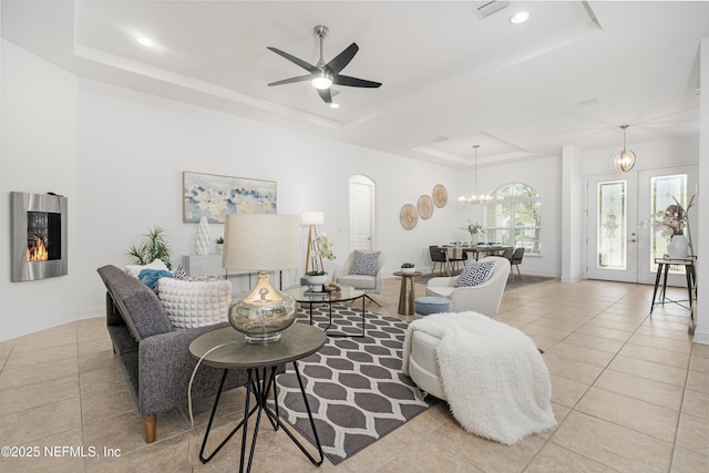 living room with arched walkways, a raised ceiling, visible vents, and light tile patterned floors