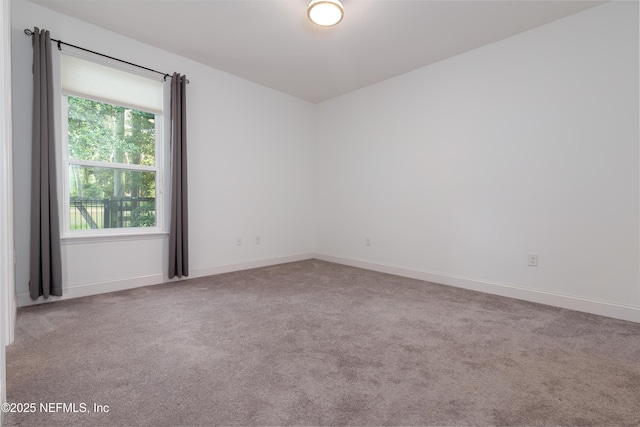 unfurnished room featuring light carpet and baseboards