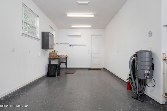 garage featuring an AC wall unit and baseboards