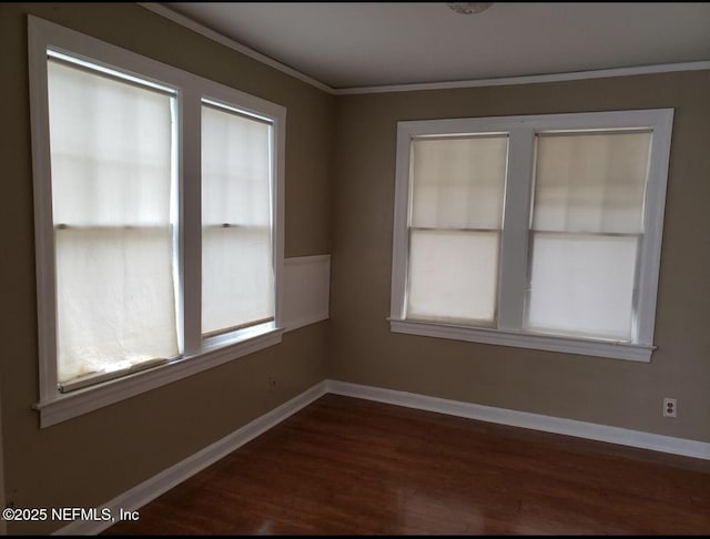 empty room featuring dark wood-style floors, plenty of natural light, and baseboards