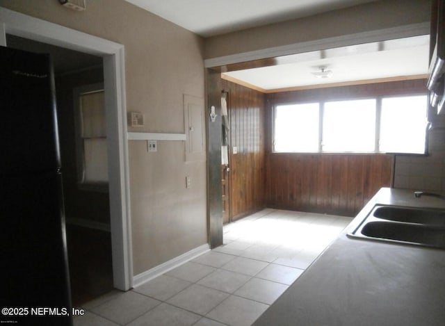 kitchen featuring light tile patterned floors, a sink, and wooden walls