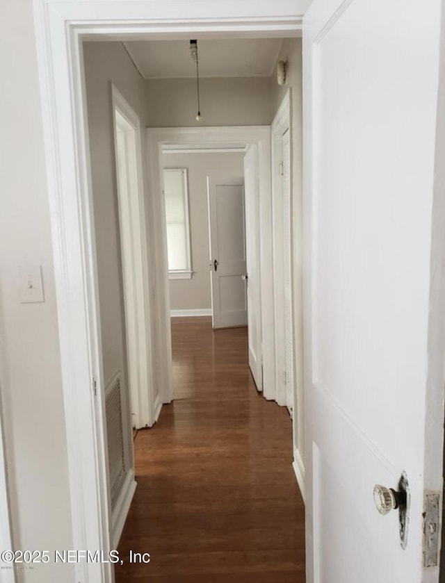 hall featuring dark wood-style floors, attic access, and baseboards