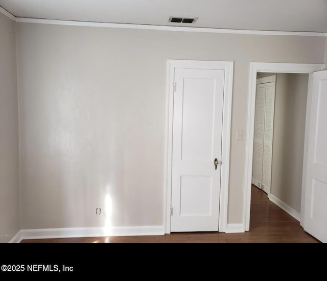 unfurnished bedroom featuring baseboards, visible vents, dark wood-style flooring, and ornamental molding