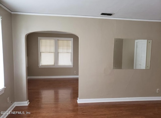 unfurnished room with ornamental molding, dark wood-style flooring, visible vents, and baseboards