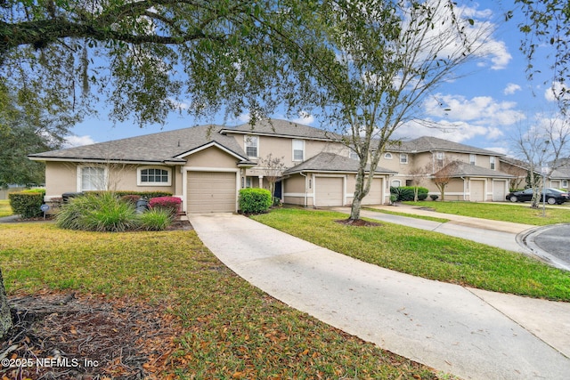 traditional-style house featuring stucco siding, an attached garage, a front yard, a residential view, and driveway