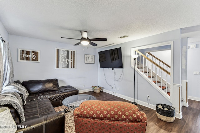 living area featuring dark wood finished floors, visible vents, a ceiling fan, a textured ceiling, and baseboards