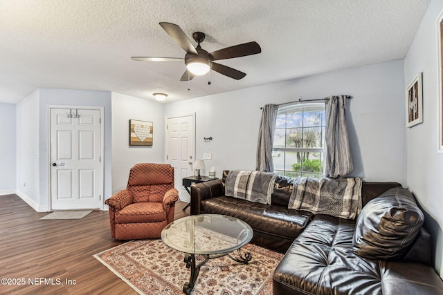 living area featuring a ceiling fan, dark wood finished floors, a textured ceiling, and baseboards