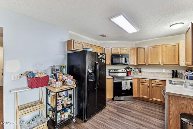 kitchen with visible vents, dark wood-style floors, light countertops, black appliances, and a sink