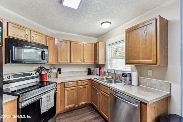 kitchen featuring dark wood-style flooring, brown cabinets, stainless steel appliances, light countertops, and a sink