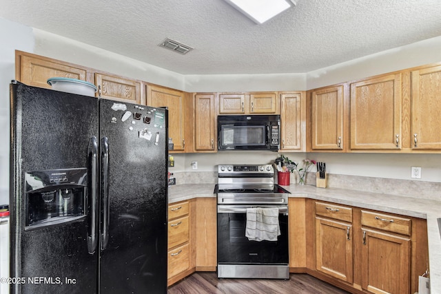 kitchen featuring a textured ceiling, dark wood-type flooring, visible vents, light countertops, and black appliances