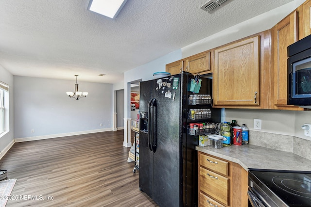 kitchen with brown cabinets, decorative light fixtures, light countertops, wood finished floors, and black fridge