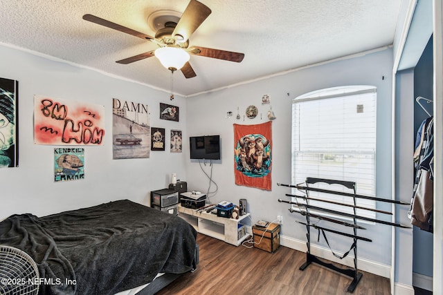 bedroom with a textured ceiling, dark wood-style flooring, a ceiling fan, and baseboards