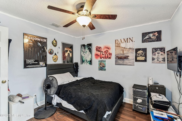 bedroom featuring baseboards, visible vents, ceiling fan, dark wood-type flooring, and a textured ceiling