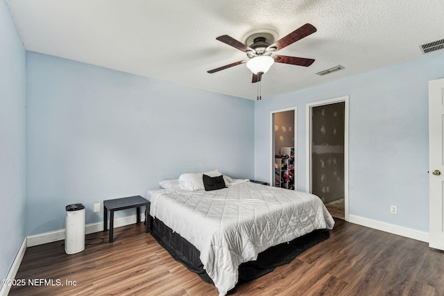 bedroom with visible vents, a textured ceiling, baseboards, and wood finished floors