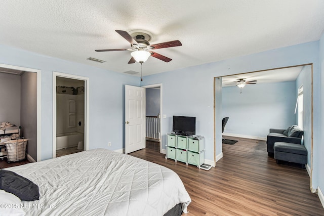 bedroom featuring dark wood-style floors, baseboards, visible vents, and a textured ceiling