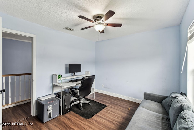 office space with dark wood finished floors, visible vents, a ceiling fan, a textured ceiling, and baseboards