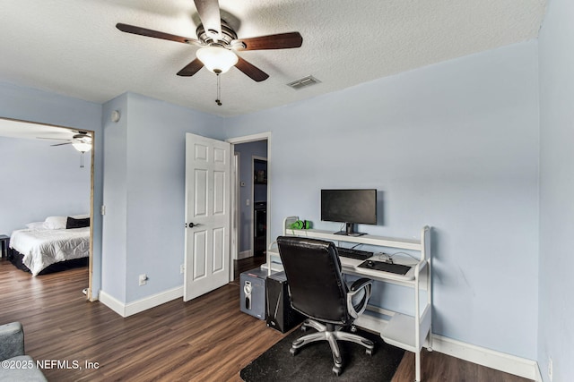 office space featuring dark wood-type flooring, visible vents, a textured ceiling, and baseboards