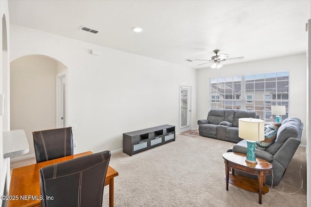 carpeted living room with arched walkways, recessed lighting, visible vents, ceiling fan, and baseboards