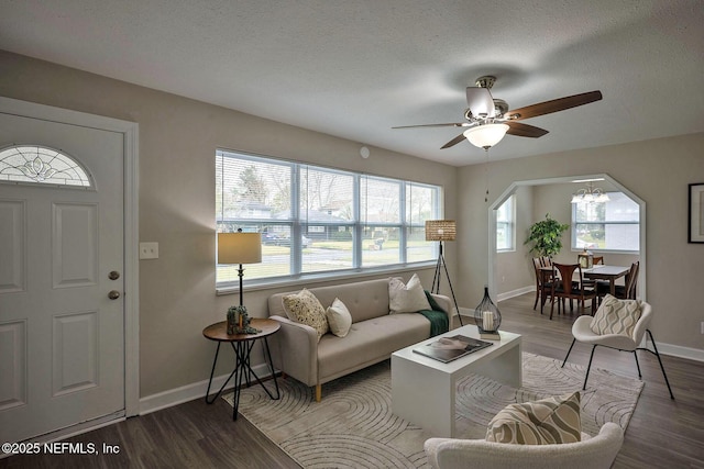 living room featuring arched walkways, a textured ceiling, and wood finished floors