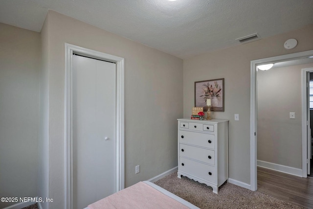 bedroom featuring a textured ceiling, visible vents, and baseboards