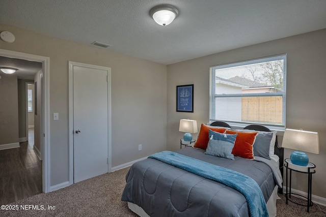 bedroom with dark colored carpet, visible vents, a textured ceiling, and baseboards