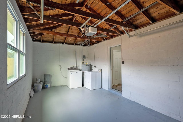 garage with concrete block wall, washing machine and dryer, and a garage door opener