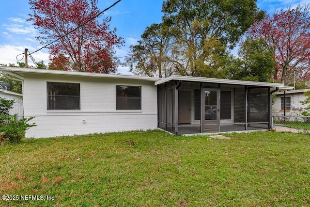 rear view of house with a sunroom, fence, and a lawn