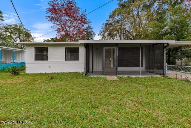 back of property with a sunroom and a lawn