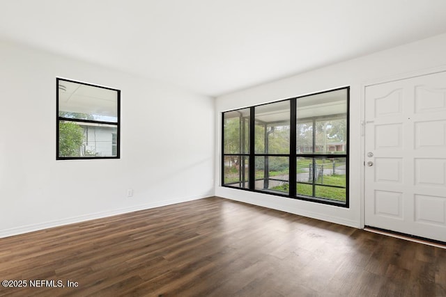 spare room featuring dark wood finished floors and baseboards