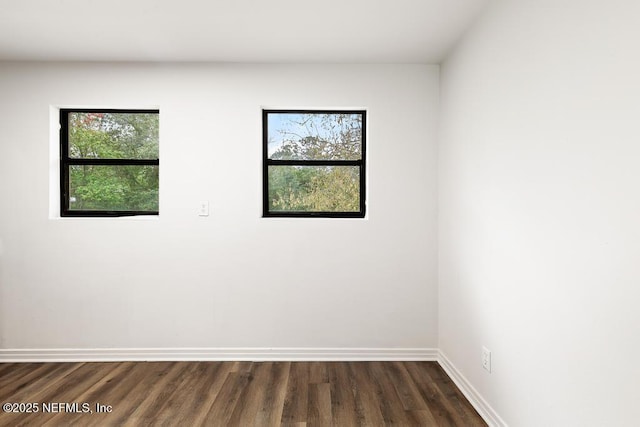 unfurnished room with baseboards, dark wood-style flooring, and a wealth of natural light