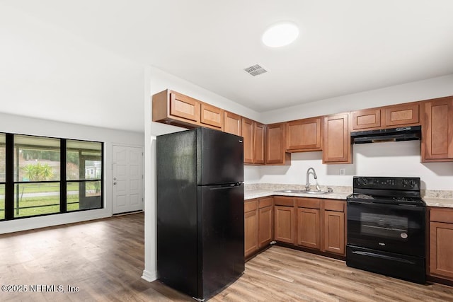 kitchen featuring under cabinet range hood, a sink, visible vents, brown cabinets, and black appliances